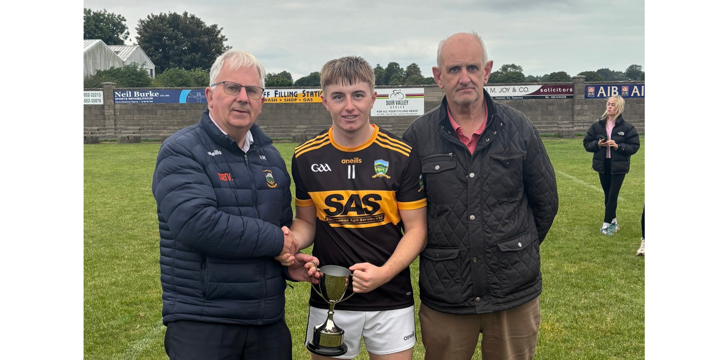 St Patrick's captain Finn Madigan receives the cup from South Tipperary GAA Chairman and fellow St Patrick's clubman Nicholas Moroney. Also included is Seamus Walsh, Vice-Chairman of South Tipp GAA