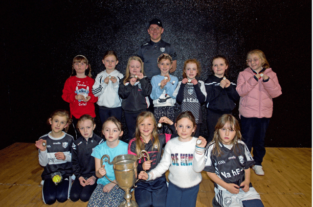 Carrick Swan GAA Under 8 camogie players with the medals they received at the ceremony and the South Senior Hurling Cup. Swan Senior Hurling team captain Dean Waters is standing at the back.