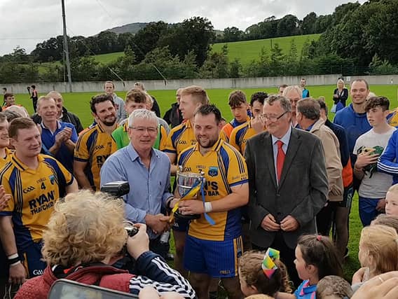 Ballinahinch captain Donnacha McGrath pictured accepting the cup from competition sponsor Denis Quirke.