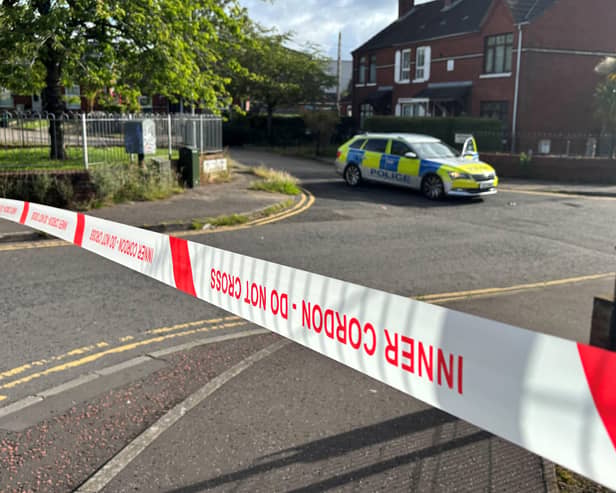 A police car on a street within a taped off cordon